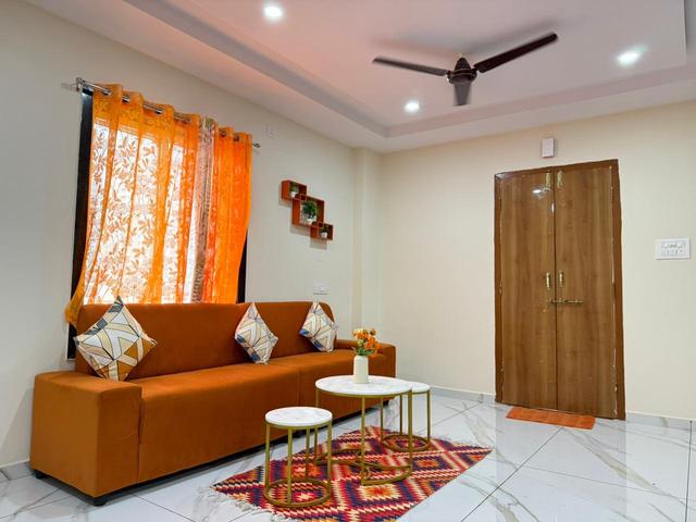 Living area with orange sofa, cushions and nesting tables